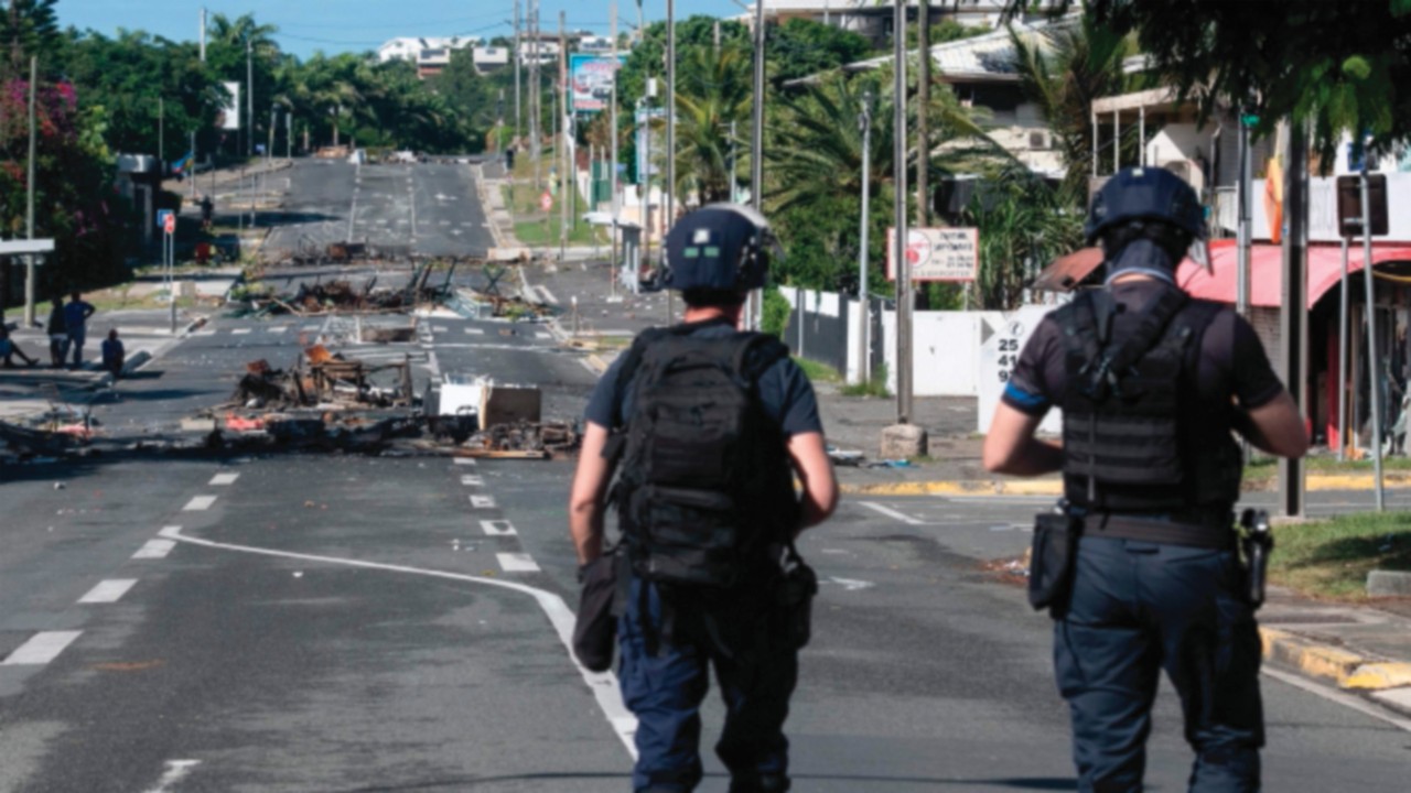 TOPSHOT - Police patrol a street blocked by debris and burnt out items following overnight unrest in ...